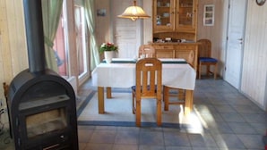 A cozy room with a dining table, chairs, a cabinet, and a wood-burning stove. - Ferienhaus mit Sauna im Ferienpark Mirow (Mirow)