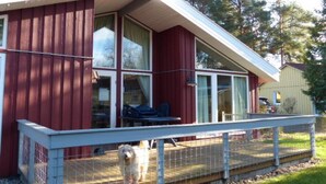 A house with a red exterior, large windows, and a covered porch area. - Ferienhaus mit Sauna im Ferienpark Mirow (Mirow)