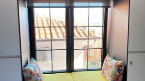 Una habitación con un asiento junto a la ventana, con cojines amarillos y almohadas coloridas.