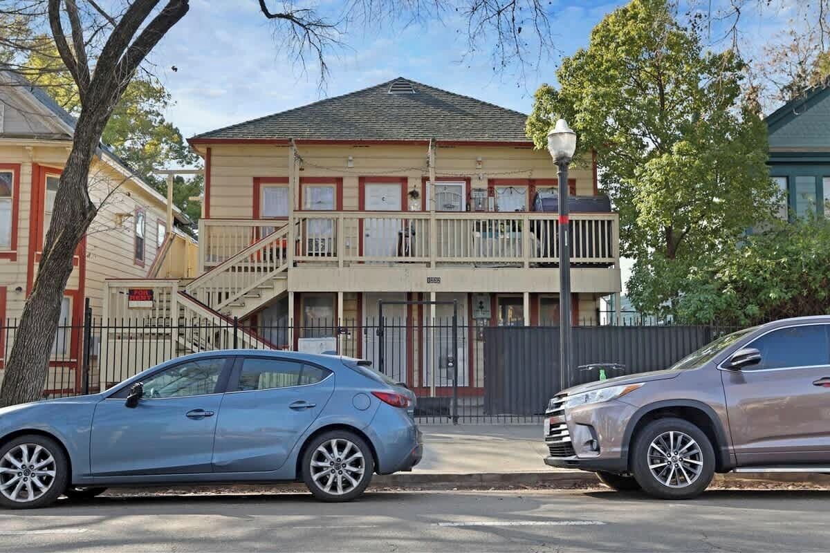 A two-story building with a balcony, a staircase, and a gated entrance.