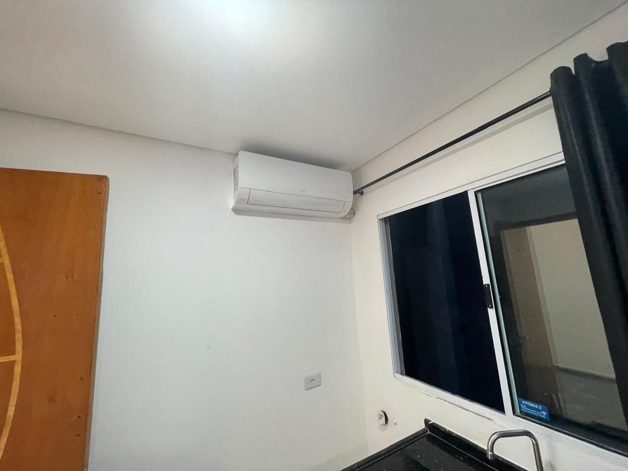 Una habitación pequeña y limpia con ventana, puerta y aire acondicionado de pared.