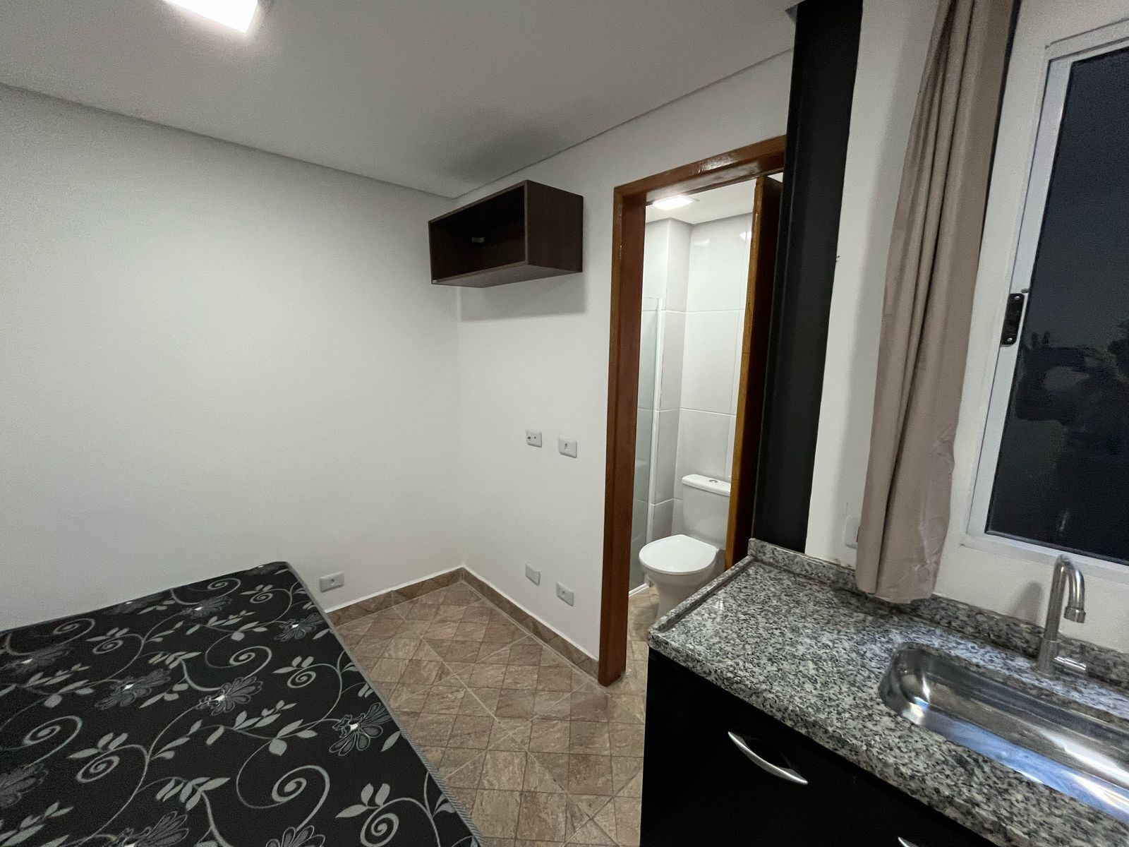 A small, clean room with a bed, a sink, and a toilet.