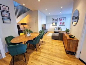 Una sala moderna con una mesa de comedor de madera, sillas color turquesa, un sofá gris y un aparador de madera.