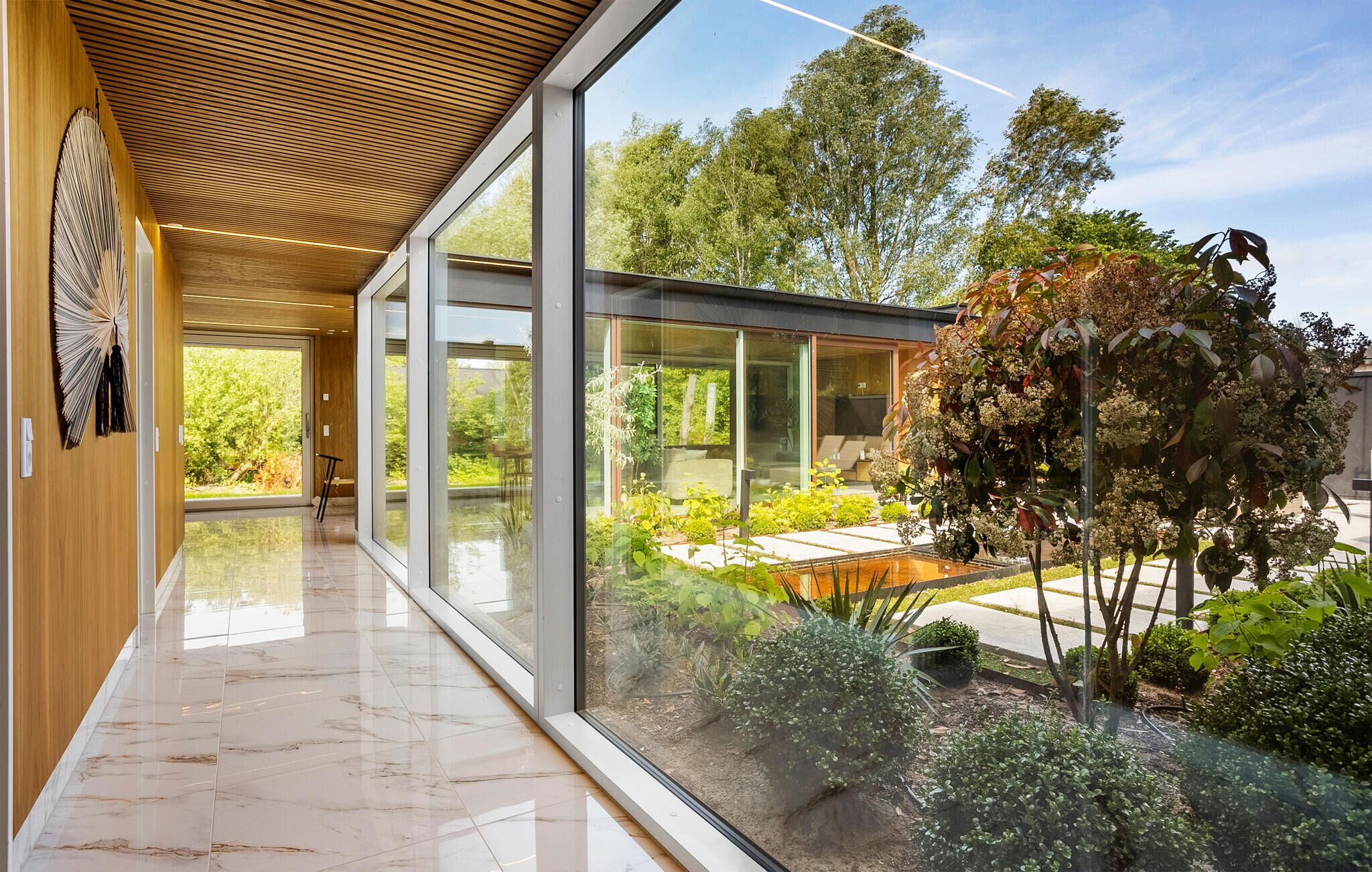 Un intérieur moderne avec un mur de verre donnant sur un jardin.