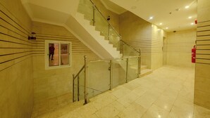 A modern interior with a glass railing staircase, tiled walls, and a clean, well-lit space. - أحلى الليالي للشقق الفندقية Ahla Al Layali Hotel Apartments (Yanbu)