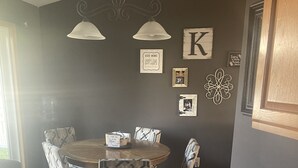 A dining area with a round table, patterned chairs, and a black storage unit with containers.
