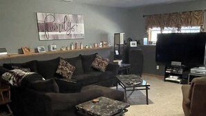 A living room with a dark-colored sofa, a coffee table, and a flat-screen TV.