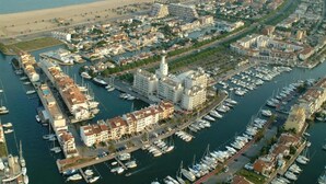 An aerial view of a coastal marina with multiple docks, boats, and buildings. - Relaxing Apt Near the Beach (Castello d'Empuries)