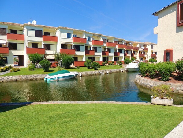 A multi-story hotel with balconies, a canal, and a boat docked by the water.