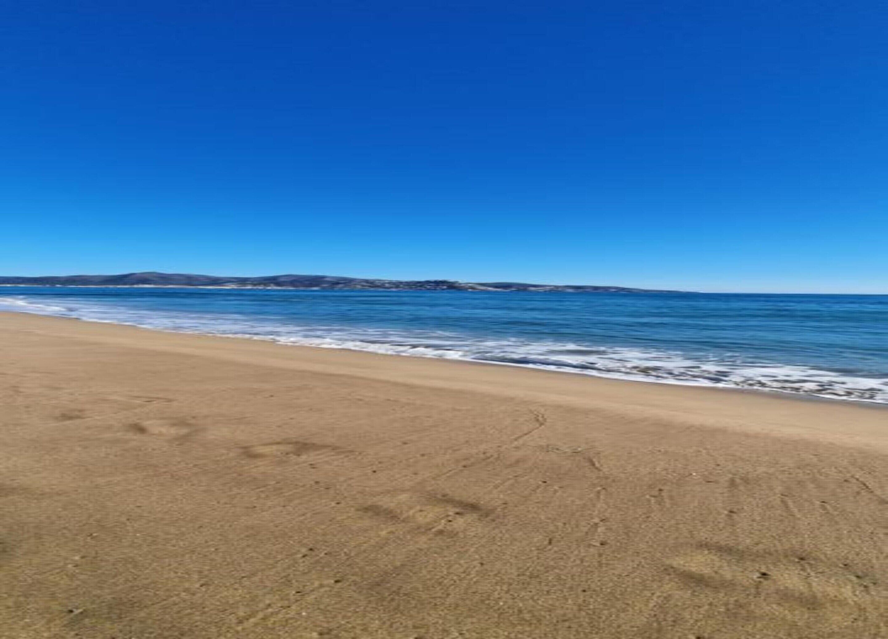 A beach with a clear sky and calm sea.