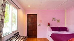 A bedroom with a bed, a bench, a wooden door, and a window with curtains. - PRAKAI RESORT (Photharam)