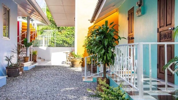 A courtyard with a gravel path, potted plants, and a white railing. - PRAKAI RESORT (Photharam)