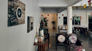 A spacious living area with a coffee-themed wall art, a wooden table with jars, a floral chair, and a cozy seating arrangement. - PRAKAI RESORT (Photharam)