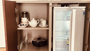 Eine kompakte Küche mit einem eingebauten Kühlschrank, einer Mikrowelle und einem kleinen Spülbecken.