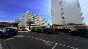 A multi-story building with a prominent 'CENTER' sign, a parking lot with several cars, and a clear blue sky.