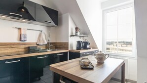 Eine moderne Küche mit dunklen Schränken, einer Holztischplatte und einem Esstisch mit Teekanne und Tasse.