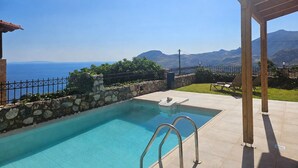 A swimming pool with a stone wall and metal railing, a pergola, and a view of the sea and mountains. - Villa Sellia-Julie (Sellia)