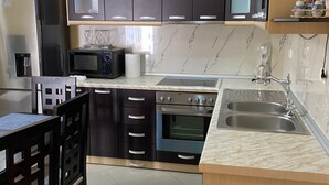 A modern kitchen with dark cabinets, a microwave, a stove, and a sink.
