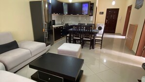 A modern living room with a sofa, a coffee table, and a dining area with chairs and a table.