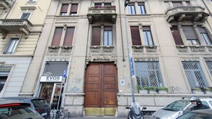 A building with a large wooden door, multiple windows, and a sign for 'EVOS'. - VivimiHome-Stelvio House (Milan)