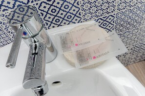 A bathroom sink with a faucet, a soap dispenser, and a patterned blue and white background. - VivimiHome-Stelvio House (Milan)