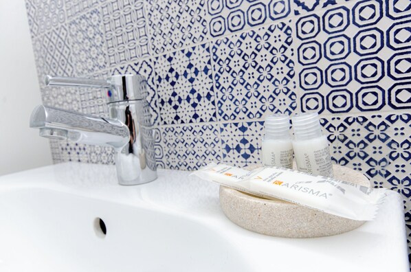 A bathroom with a white sink, a modern faucet, and patterned tiles in the background.