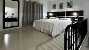 A bedroom with a bed, a mirror, and a window with curtains. - Grande Hotel Paranavaí (Paranavaí)