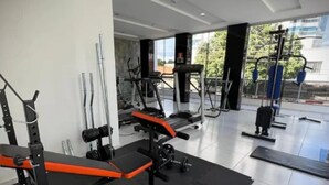 A modern gym with various exercise equipment, including a bench press, weight racks, and cardio machines. - Grande Hotel Paranavaí (Paranavaí)