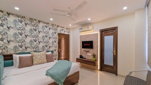 A bedroom with a bed, a TV, a ceiling fan, and a wall-mounted air conditioner. - Auro Bliss - An Opulent 3bhk Penthouse in Dehradun (Dehradun)