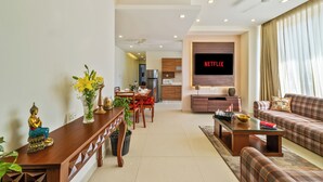 A modern living room with a sofa, coffee table, and a dining area with chairs and a table. - Auro Bliss - An Opulent 3bhk Penthouse in Dehradun (Dehradun)