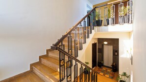 A multi-level staircase with a wooden finish and black metal railings, leading to a landing with potted plants and a door. - Auro Bliss - An Opulent 3bhk Penthouse in Dehradun (Dehradun)