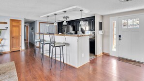 Une cuisine spacieuse dotée d’un grand îlot central, de tabourets de bar et d’un luminaire moderne au plafond.
