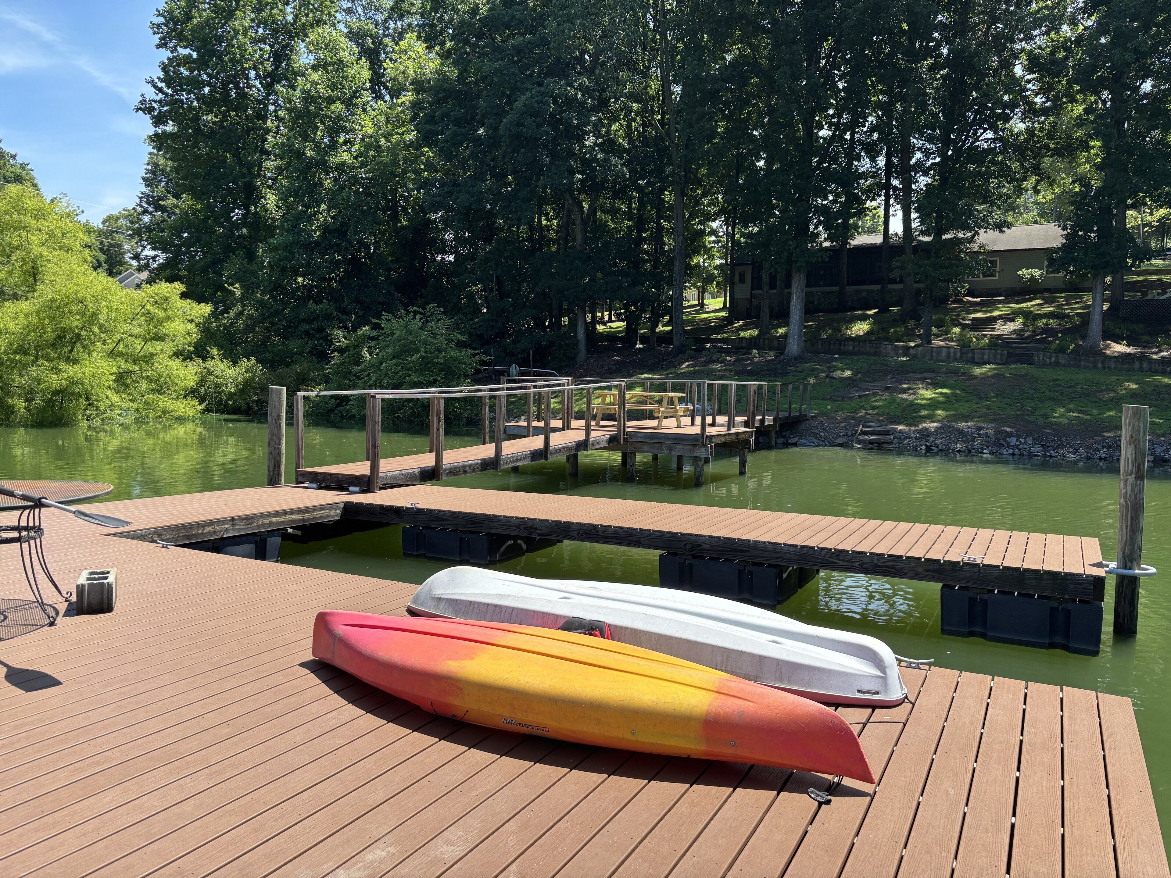 Une jetée en bois avec des kayaks et une table de pique-nique.