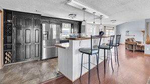 Une cuisine moderne avec des meubles en bois foncé, des appareils électroménagers en acier inoxydable et un îlot central doté de tabourets de bar.