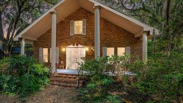 A brick house with a porch, a front door, and a small staircase leading up to the entrance.