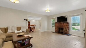 A spacious living room with a fireplace, a television, and a dining area. - Ponderosa Off The Beaten Path 5 Bedroom Farmhouse 2.7 Acres by UF (Gainesville)