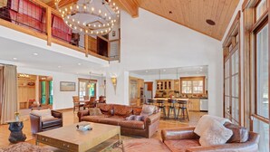 A spacious living area with leather sofas, a coffee table, and a dining area with a kitchen in the background.