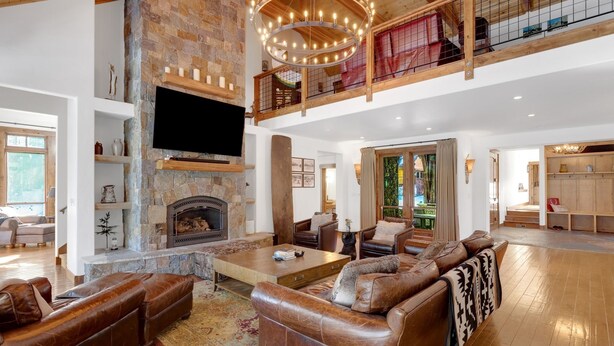 A spacious living room with a stone fireplace, leather sofas, and a large TV.
