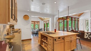 A spacious kitchen with a large island, wooden cabinets, and a dining area with a table and chairs.