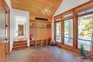 Interior de madera con piso de piedra, un banco y un pequeño árbol de Navidad.