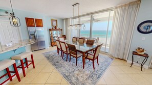 A modern kitchen with a dining area, a refrigerator, and a view of the ocean. - Oceania 504 3 Bedroom Condo (Destin)