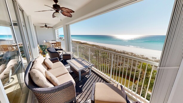 A balcony with wicker furniture, a ceiling fan, and a view of the beach. - Oceania 504 3 Bedroom Condo (Destin)