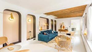A modern living room with a blue sofa, wicker chairs, and a wooden ceiling. - JUST STEPS FROM ICONIC LOUVRE,JARDIN DES TUILERIES & PLACE VENDÔME–RUE DE RIVOLI (Paris)