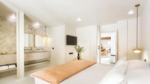 A modern bedroom with a large bed, a vanity with a mirror, and a television mounted on the wall. - JUST STEPS FROM ICONIC LOUVRE,JARDIN DES TUILERIES & PLACE VENDÔME–RUE DE RIVOLI (Paris)