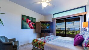 A bedroom with a bed, a television, a painting, a chair, and a balcony with a view.