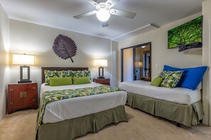 Ein Schlafzimmer mit zwei Betten, einem Deckenventilator und einer großen Blätter-Dekoration an der Wand.
