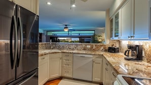A modern kitchen with stainless steel appliances, white cabinetry, and a granite countertop.