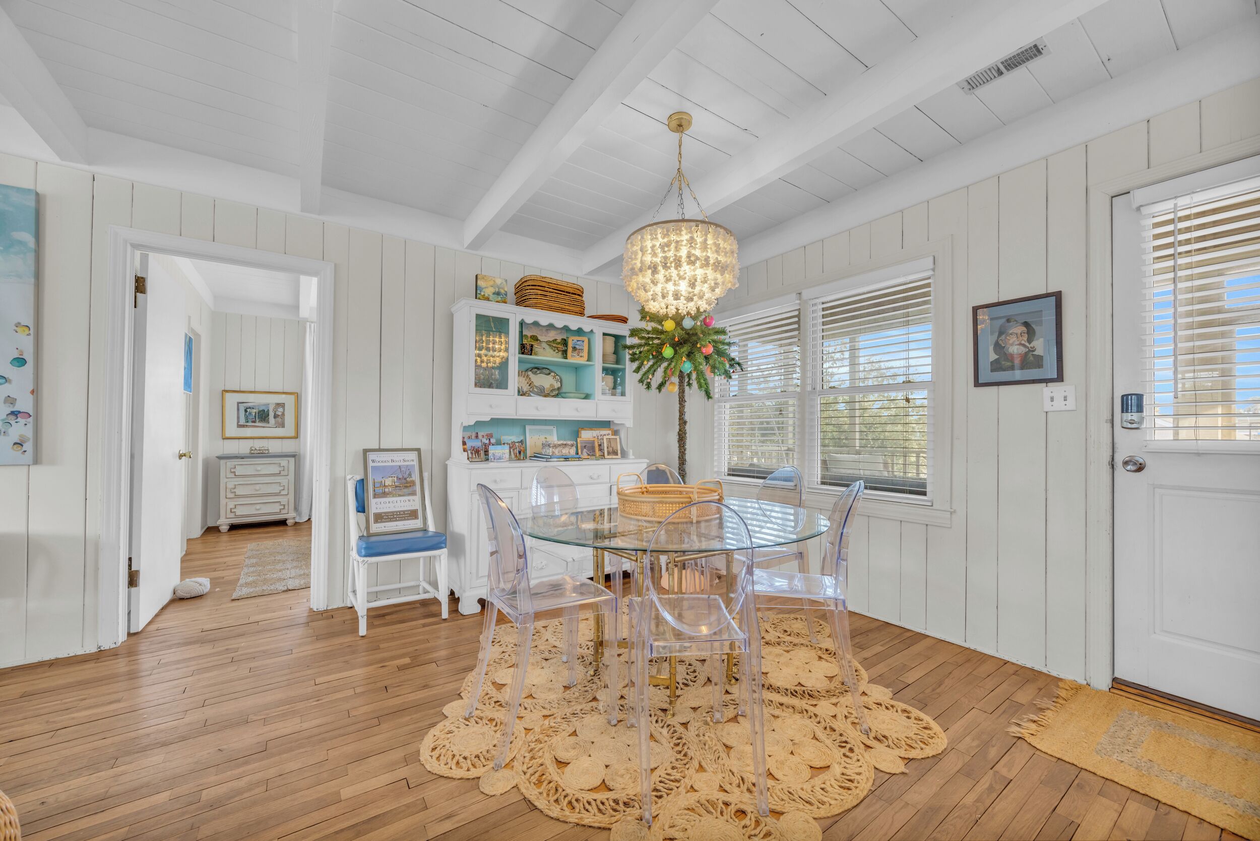 A dining area with a glass table and chairs, surrounded by white walls and wooden floors.