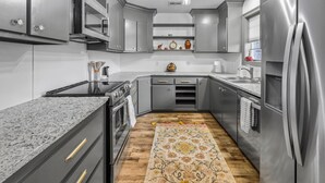 A modern kitchen with grey cabinetry, stainless steel appliances, and a wooden floor. - 3 Bedroom Family Home in Lake Charles, La (Lake Charles)