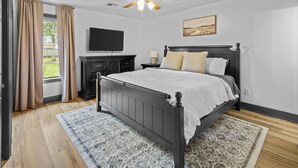A bedroom with a bed, a ceiling fan, a TV, a nightstand, and a window with curtains. - 3 Bedroom Family Home in Lake Charles, La (Lake Charles)